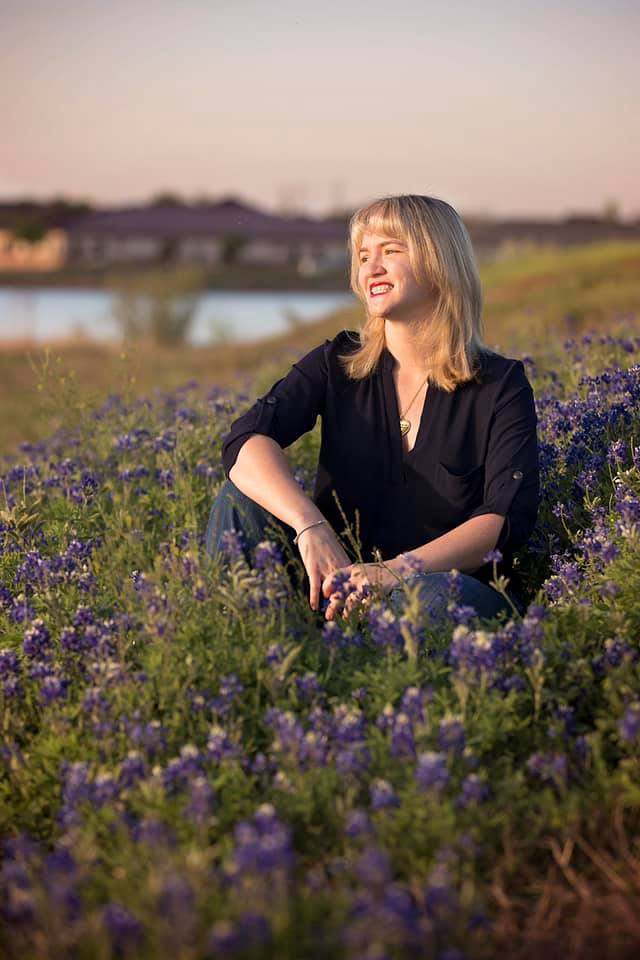 Tiffany Kohen sitting in a field of purple flowers.