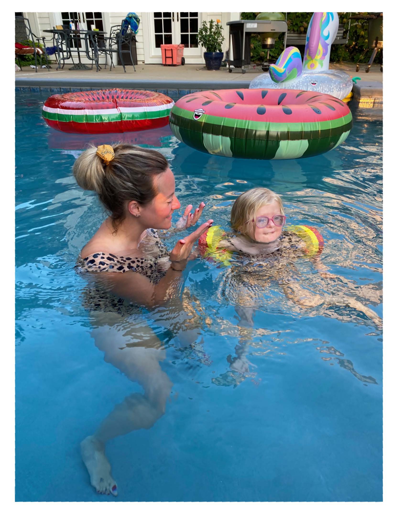 Jackie swimming with arm floats next to her mom.