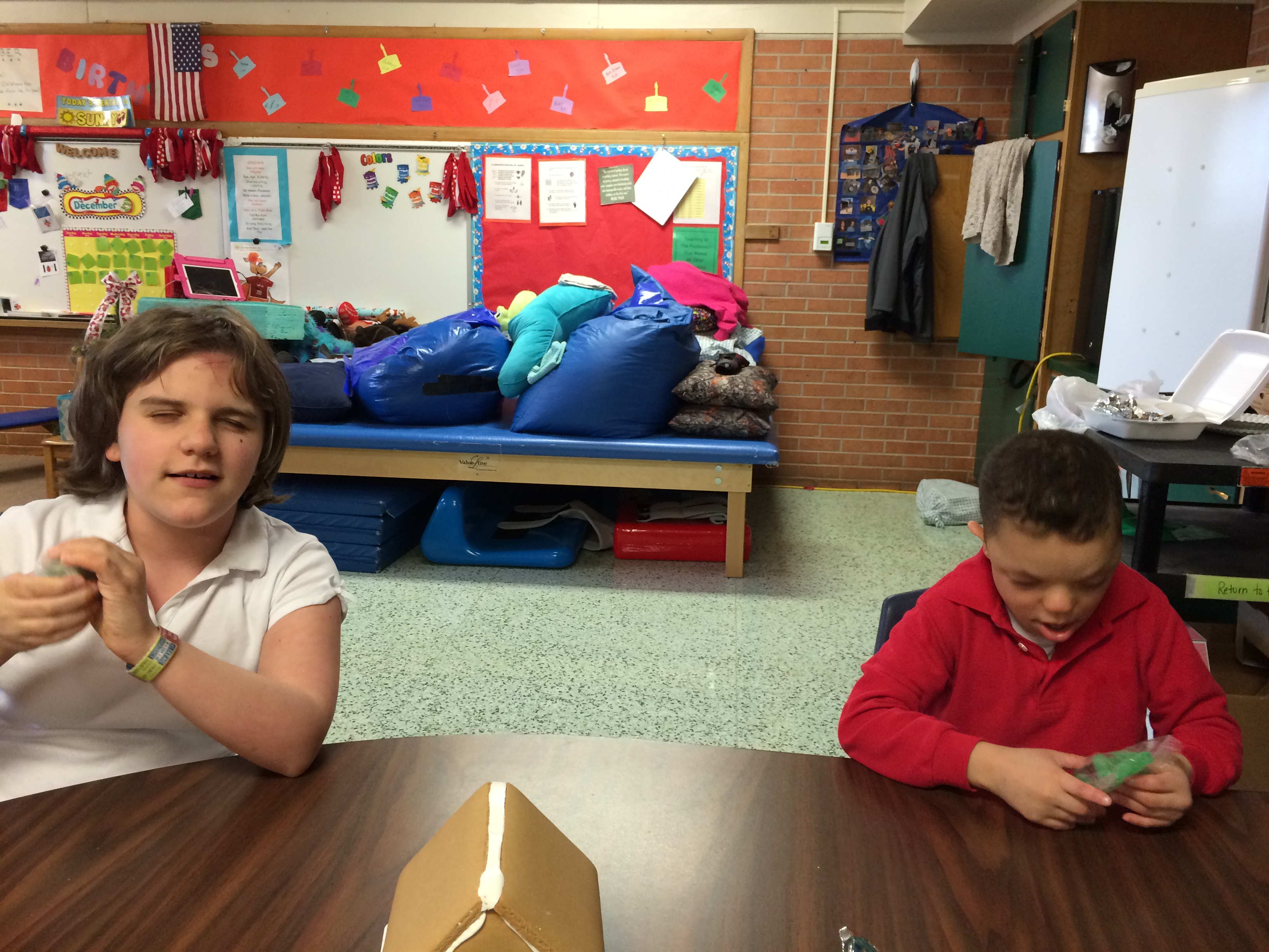 Two children sit at a desk working on a task.