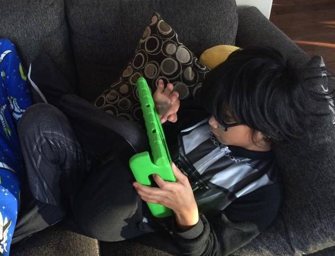 A child holds an ipad with a bright green case around it