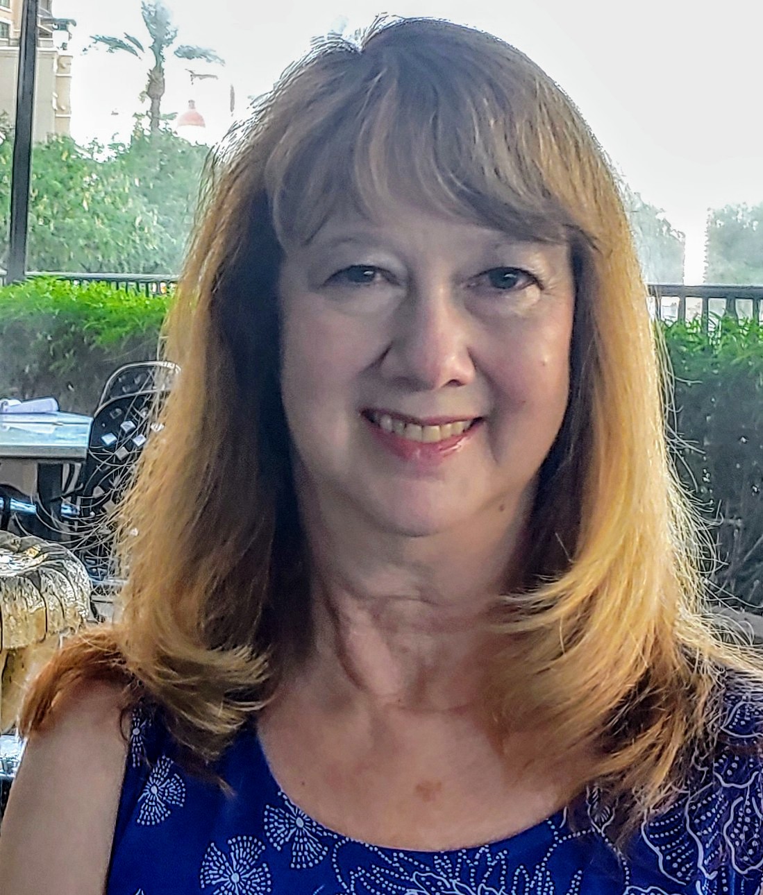 Adult woman with long brown hair smiling at camera.