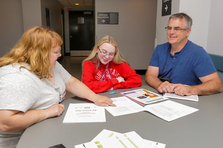 Two adults with young girl with papers.