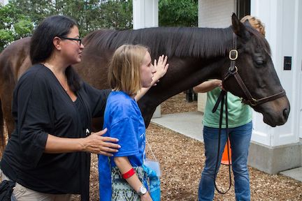 Young girl petting horse.